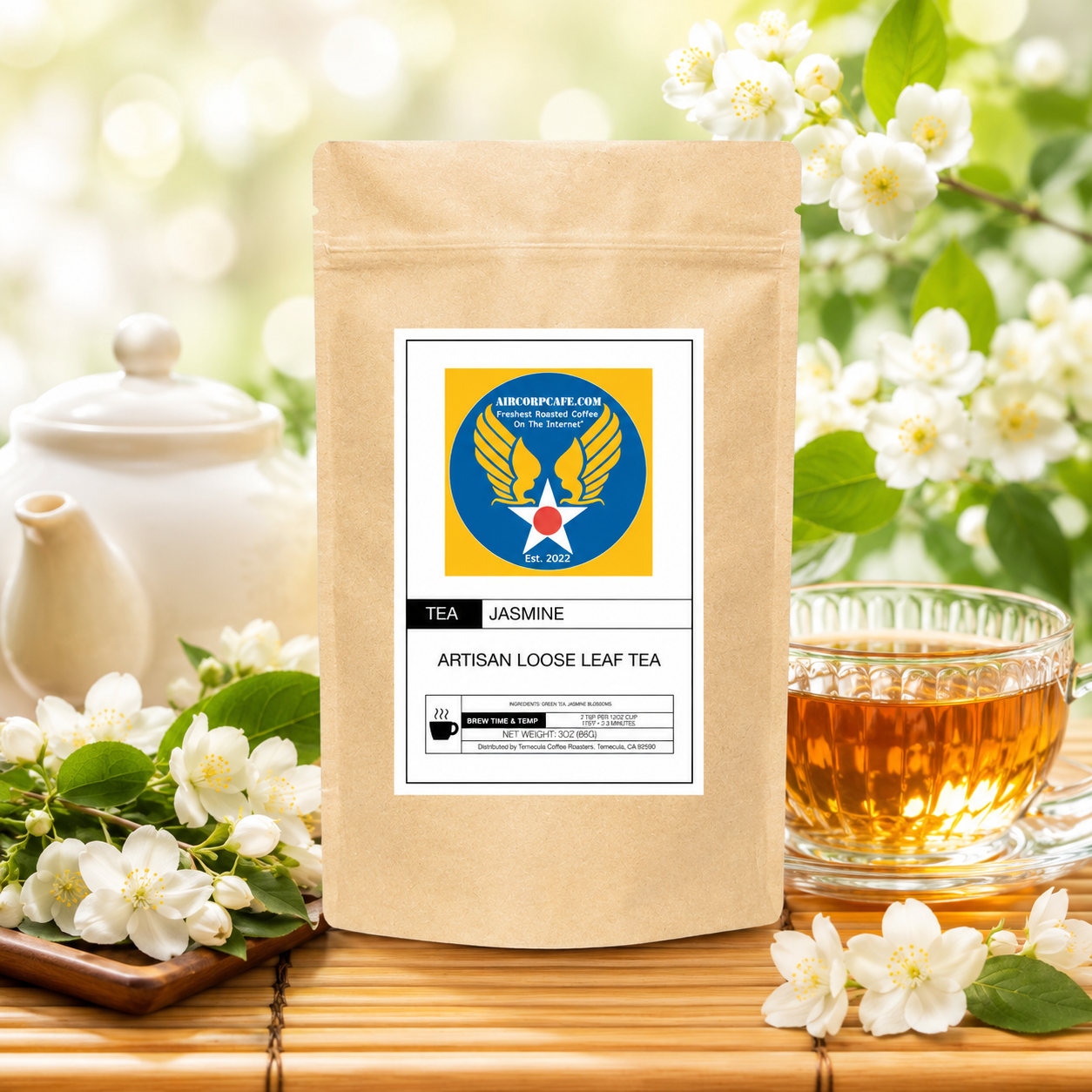 Tea package with a label, teapot, cup of tea, and jasmine flowers on a wooden surface.